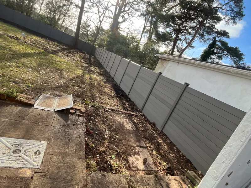 Grey composite fence panels newly installed along a garden boundary