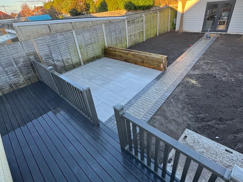 Composite decking with steps down to a porcelain patio and paved path
