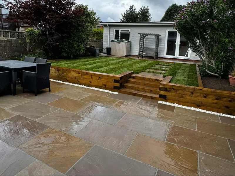Finished garden with sandstone patio, timber sleeper retaining wall, steps and a new striped lawn