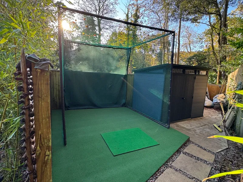 Garden golf practice net on new artificial turf beside a stepping-stone path