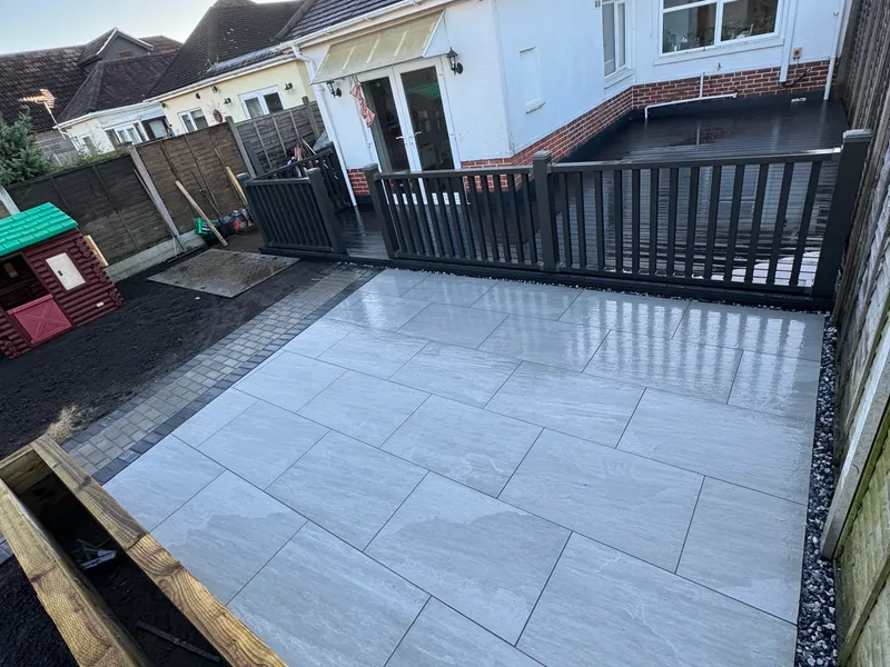 Large porcelain patio with charcoal block edging beside new decking