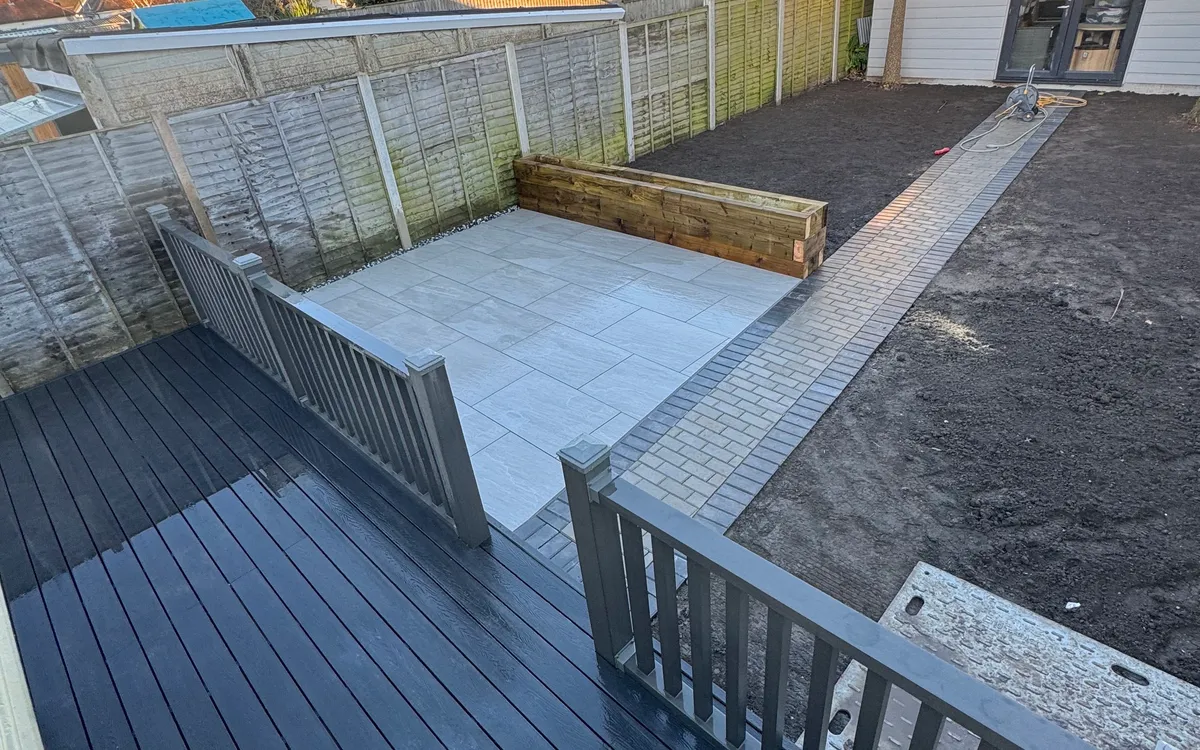 Garden mid-renovation with new composite decking, porcelain patio, sleeper planter and block-paved path
