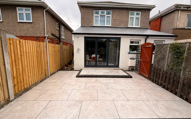 Cream porcelain patio filling a rear garden between a new close board fence and a house